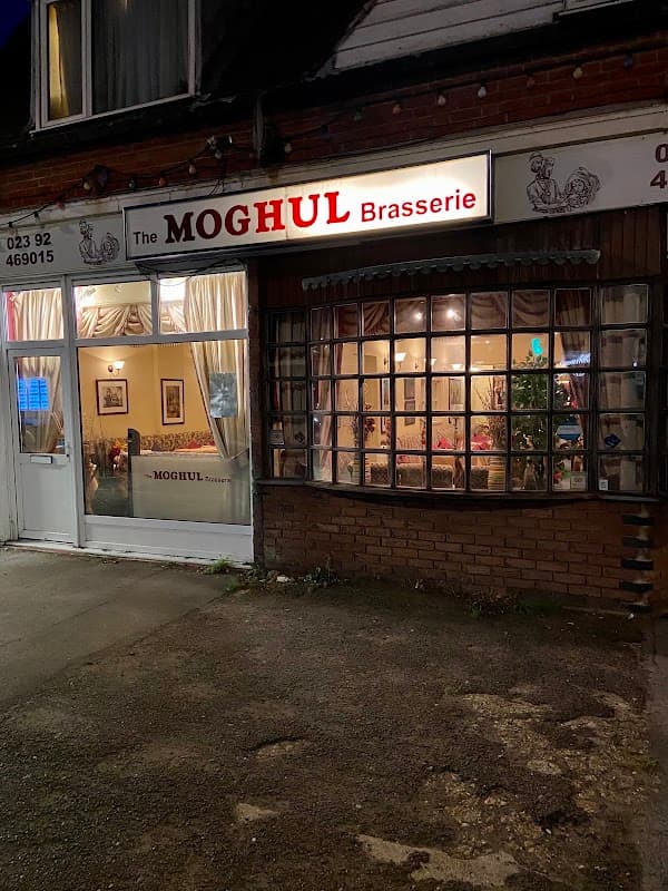 The Moghul Brasserie shopfront on Elm Grove, Hayling Island, lit up at night